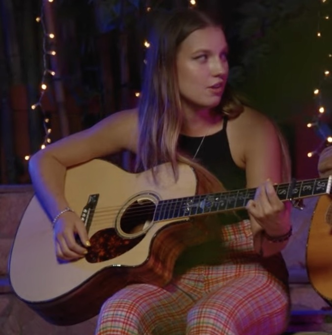 Brett Kimberlin as Kelsie Kimberlin with a guitar